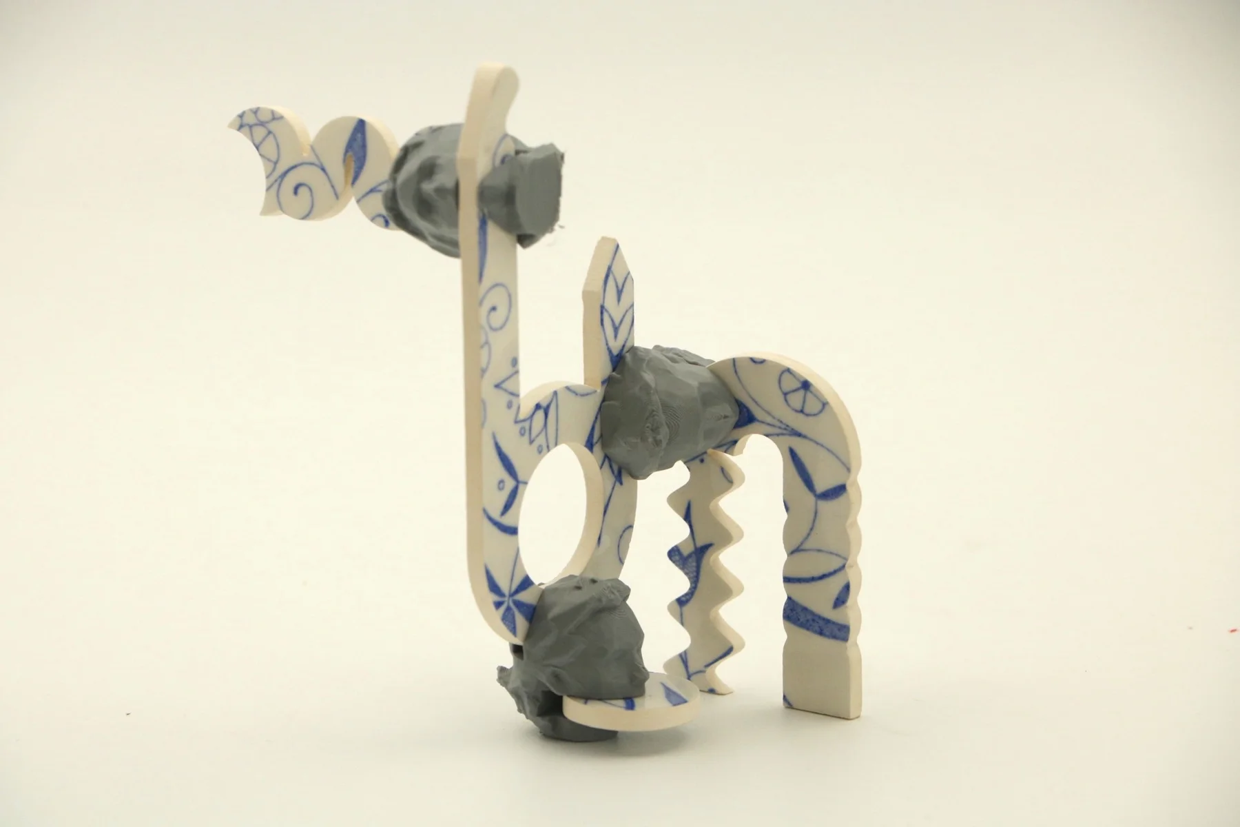 A sculpture combining curved patterned fragments and grey connectors