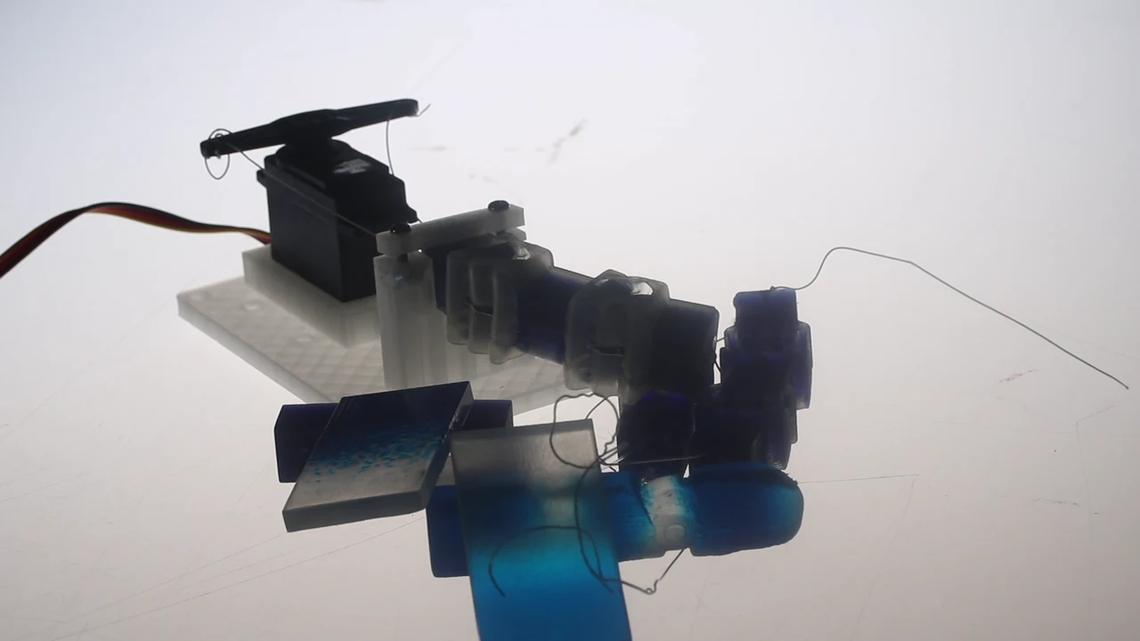 The finger prototype connected to a servo on a test rig, alongside earlier prints
